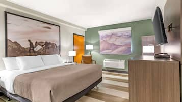 A hotel room with a large bed, a desk, a television, and two wall-mounted lamps.