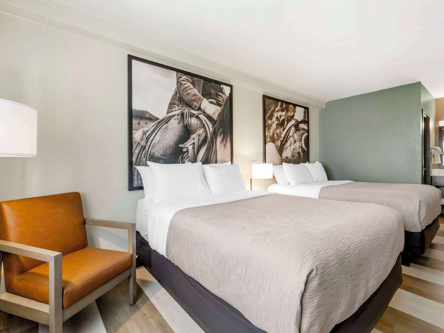 Une chambre d’hôtel avec deux lits, une chaise et des œuvres d’art accrochées aux murs.