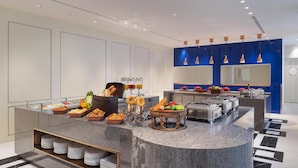 Cozinha moderna com bancada de mármore, diversos alimentos e uma parede azul como detalhe.