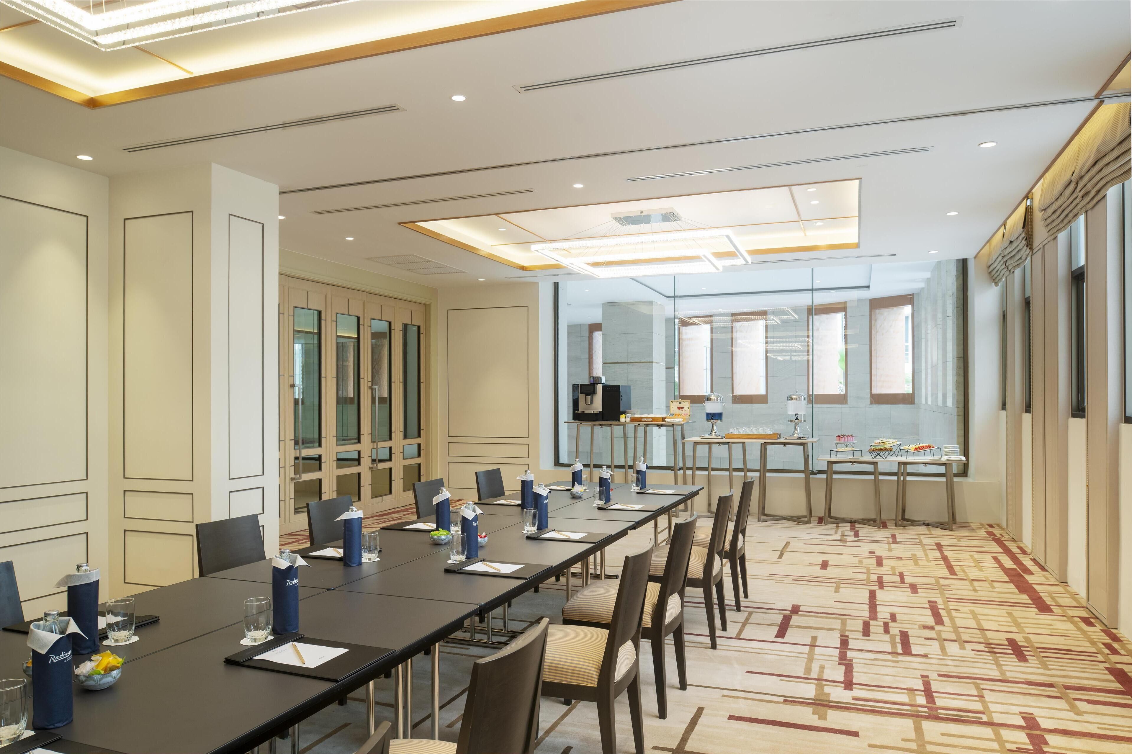 Un salón de conferencias con una larga mesa, sillas y una pantalla de televisión.