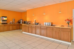 Una cocina con una encimera larga, armarios de madera y varios electrodomésticos como una cafetera y un microondas.