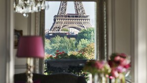 Una habitación con vistas a la Torre Eiffel a través de una ventana, un candelabro y un jarrón con flores.