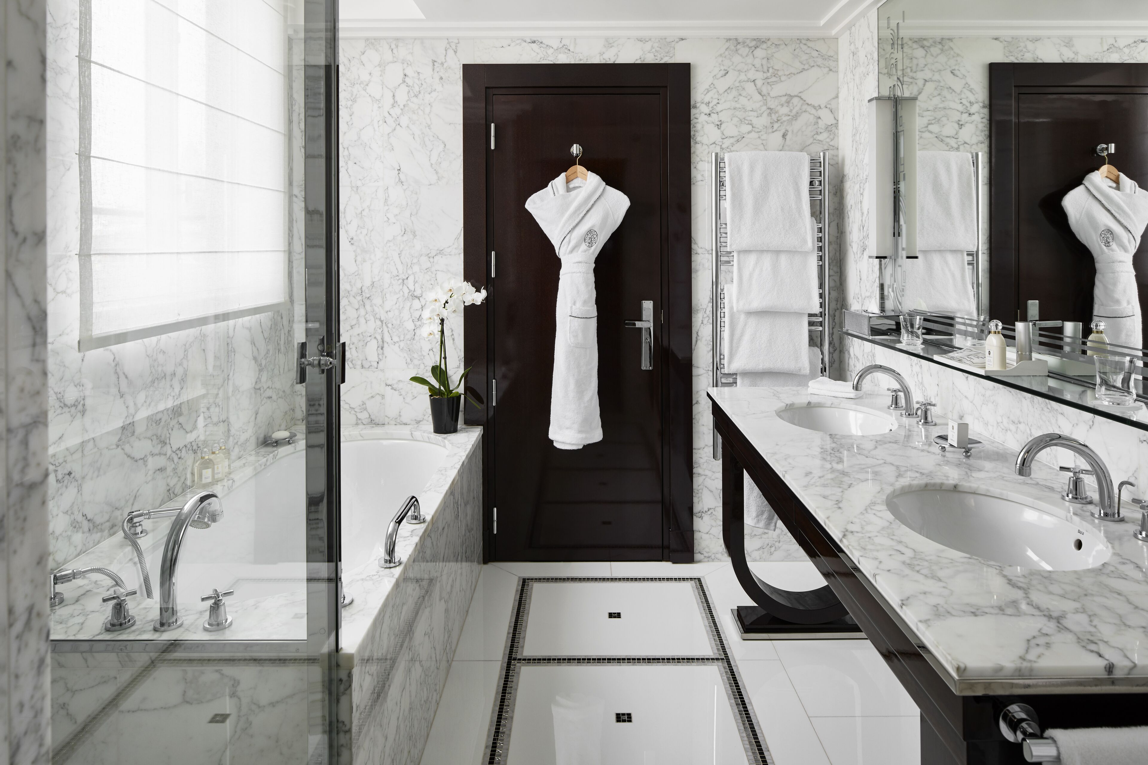 Un baño moderno con dos lavamanos, un espejo grande y una puerta oscura.