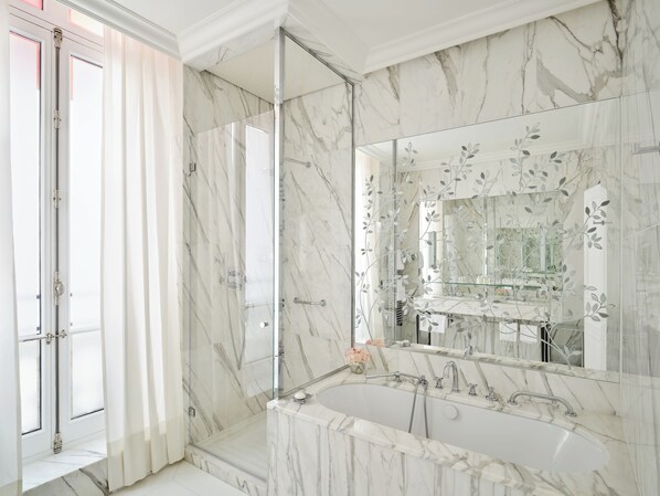 Un baño moderno con un lavabo grande de mármol, una cabina de ducha de vidrio y un espejo grande con diseño floral.