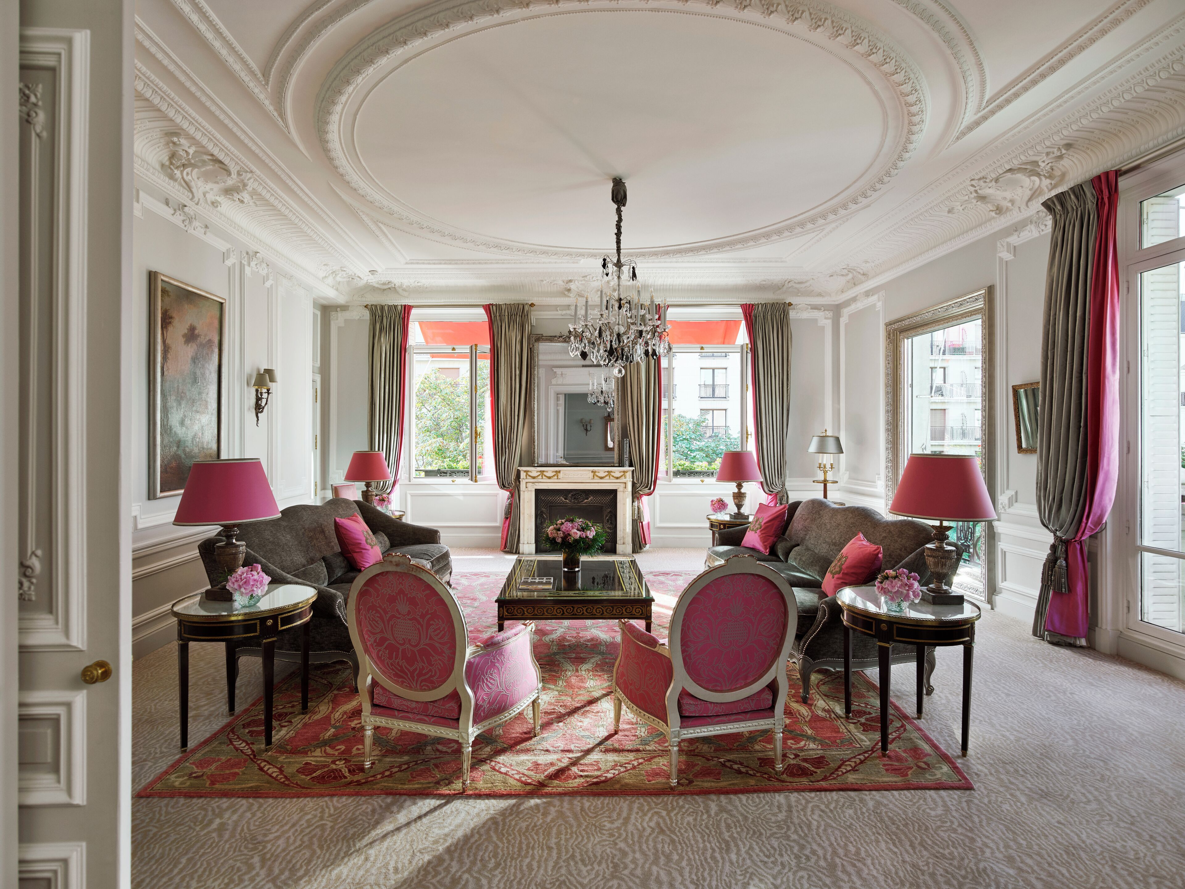 A luxurious living room with ornate ceiling, a fireplace, and elegant furniture.