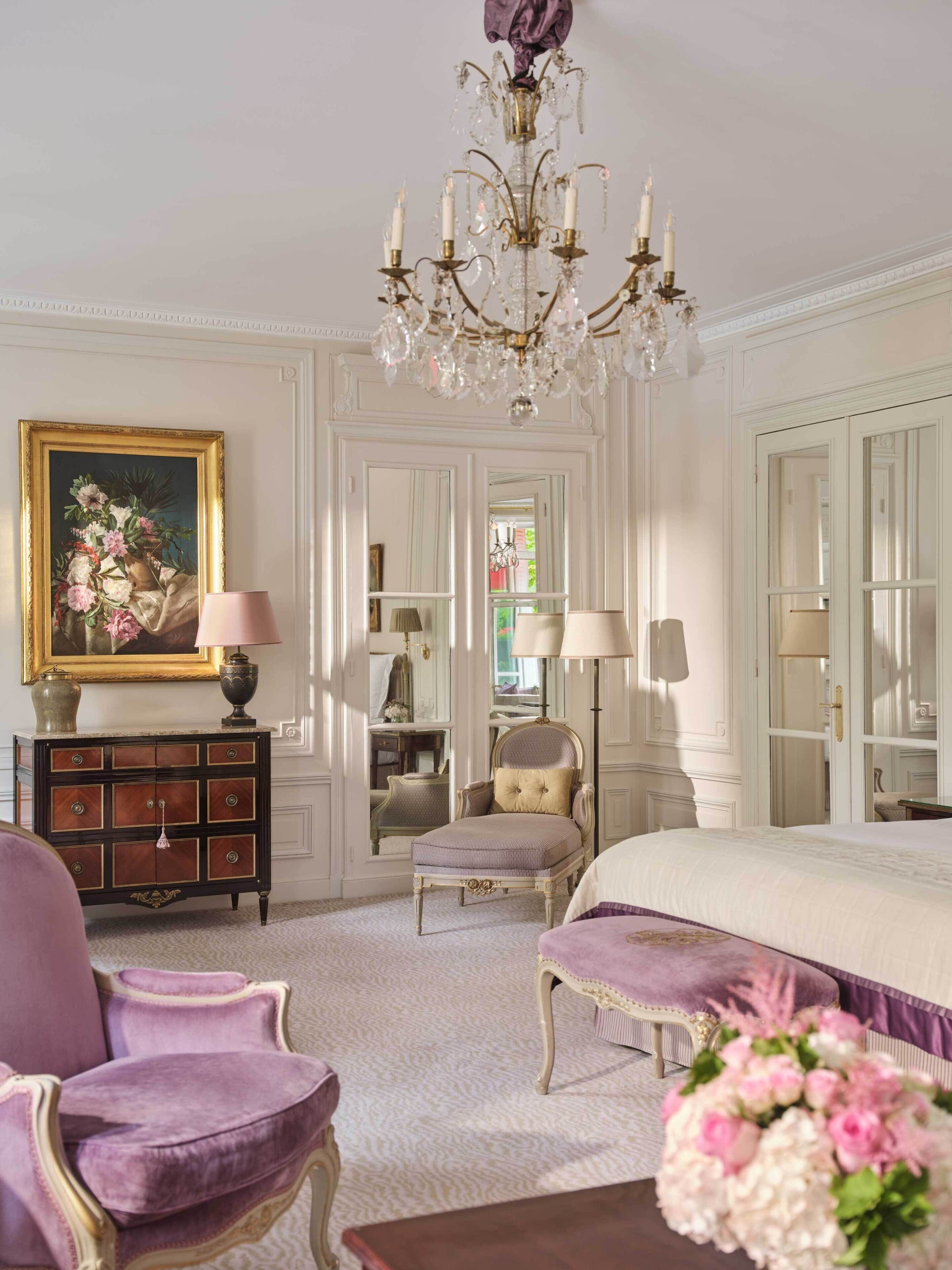 Une pièce comprenant un lit, une chaise, une commode, un lustre et un miroir.