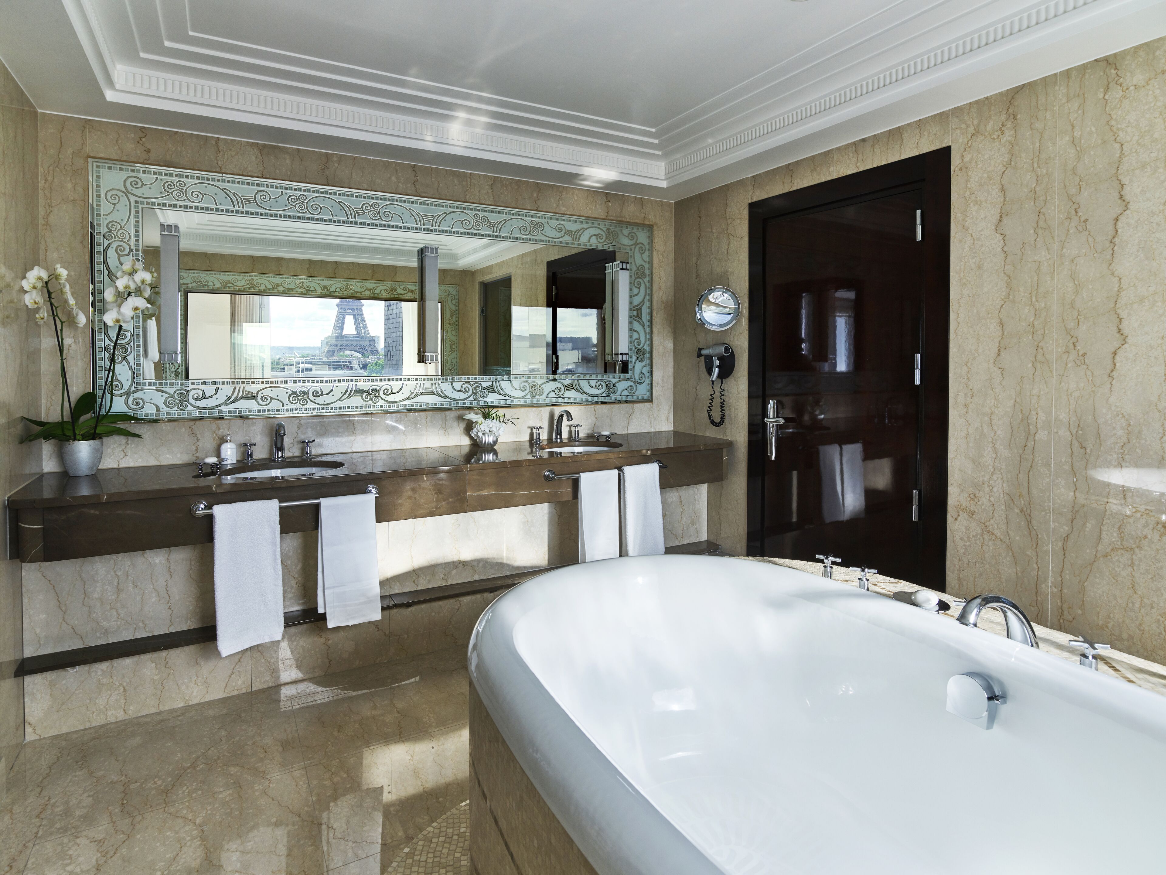 Une salle de bain luxueuse avec une grande baignoire, deux lavabos, un grand miroir et un téléphone.