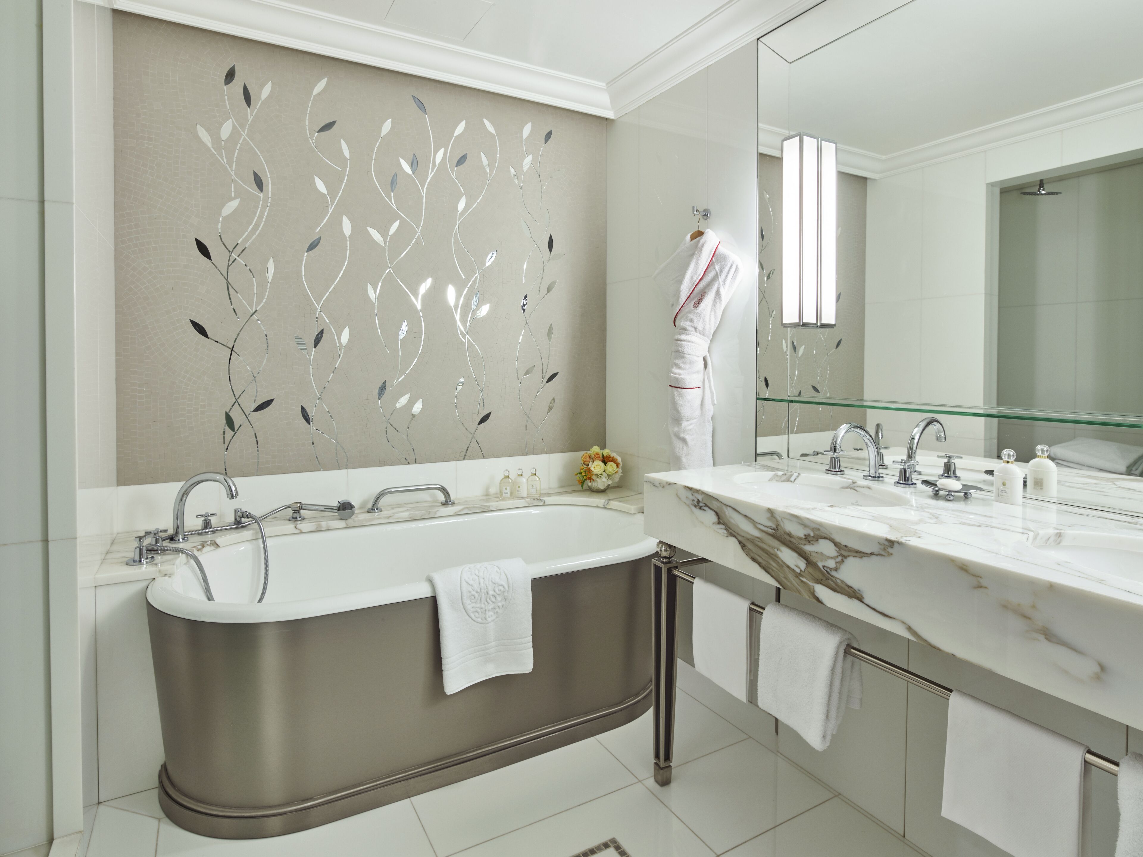 A modern bathroom with a freestanding bathtub, a large mirror, and a decorative wall panel.
