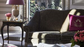A room with a view of the Eiffel Tower, a sofa, a table with a lamp, and a vase of flowers. - Hôtel Plaza Athénée - Dorchester Collection (Paris)