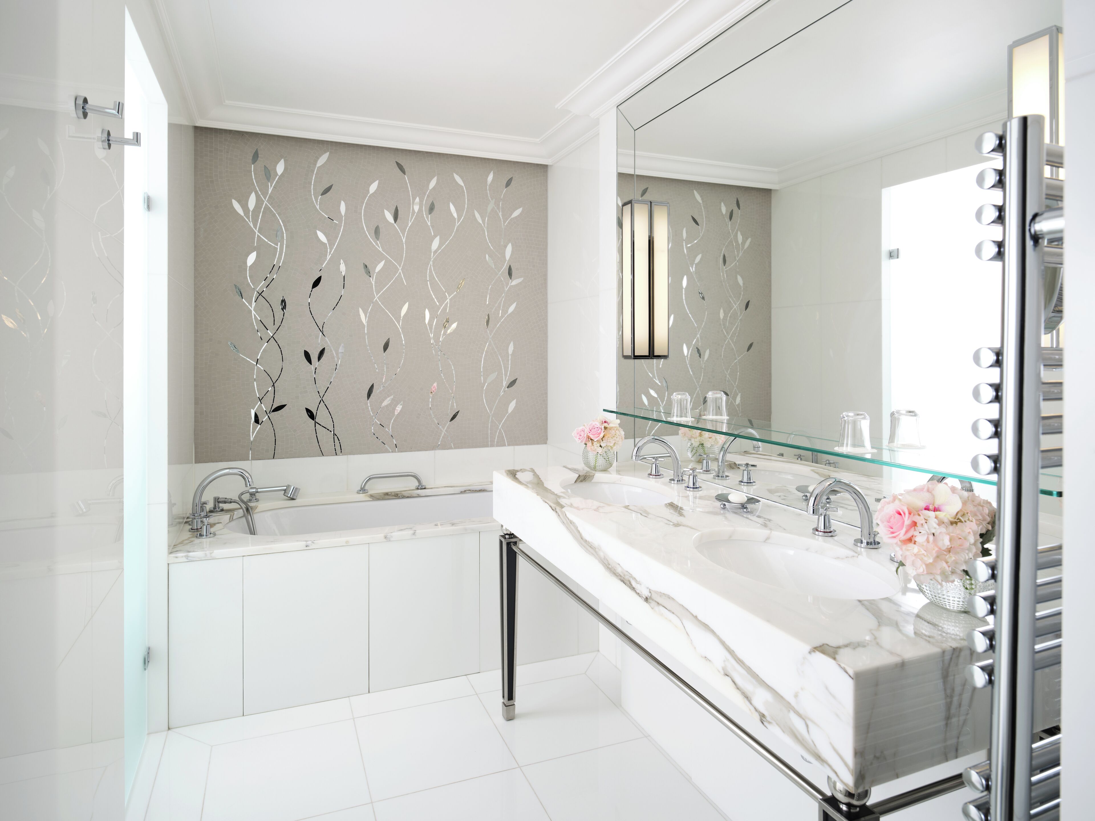 Un baño moderno con lavamanos doble, cabina de ducha con mampara de cristal y un espejo grande.