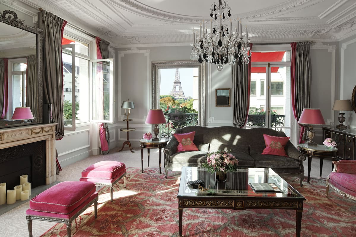 Een luxe kamer met een bank, poef en een glazen salontafel.