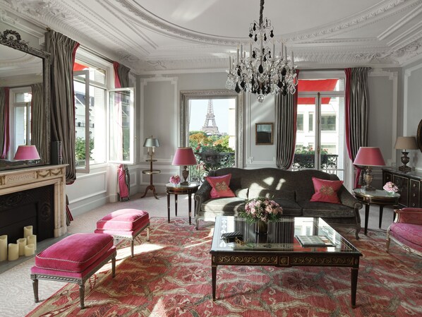A luxurious room with a sofa, ottoman, and a glass coffee table. - Hôtel Plaza Athénée - Dorchester Collection (Paris)