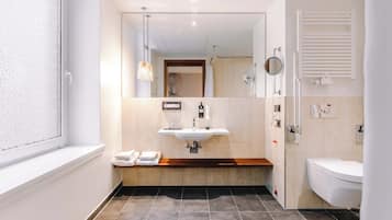 Un baño moderno con un espejo grande, un lavabo y una zona de ducha.
