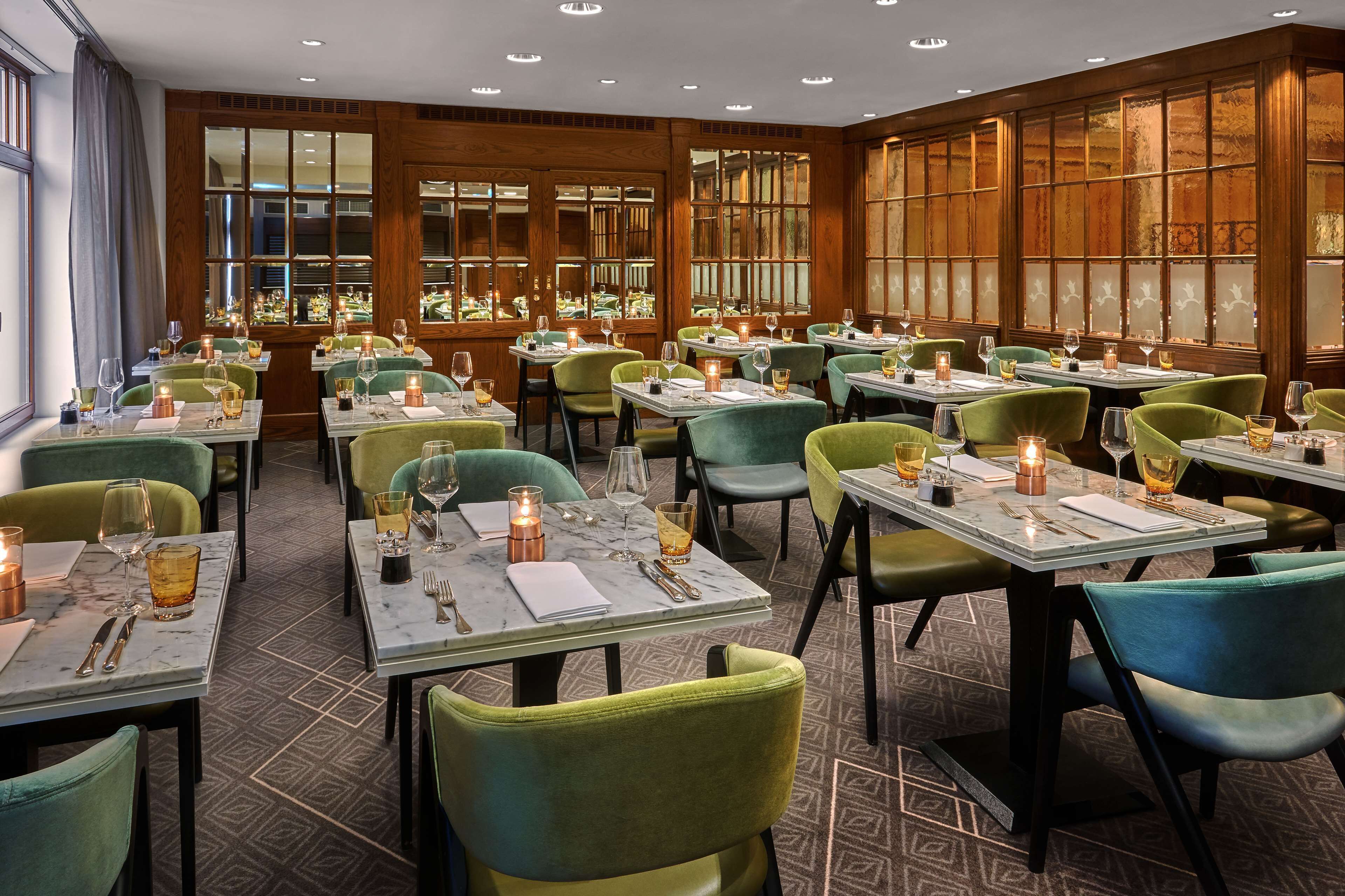 A restaurant with multiple tables, each set with wine glasses, candles, and cutlery.