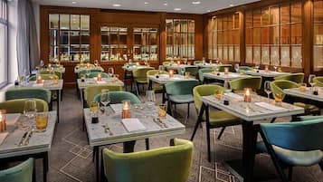 A restaurant with multiple tables, each set with wine glasses, candles, and cutlery.