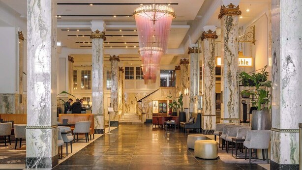 Eine großzügige Lobby mit Marmorsäulen, einem prunkvollen Kronleuchter und einer Rezeption.