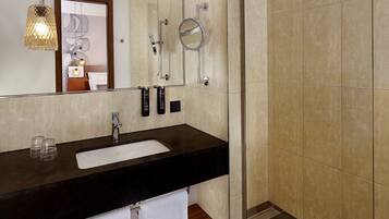 A modern bathroom with a black countertop sink, a mirror, a handheld showerhead, and a towel rack.