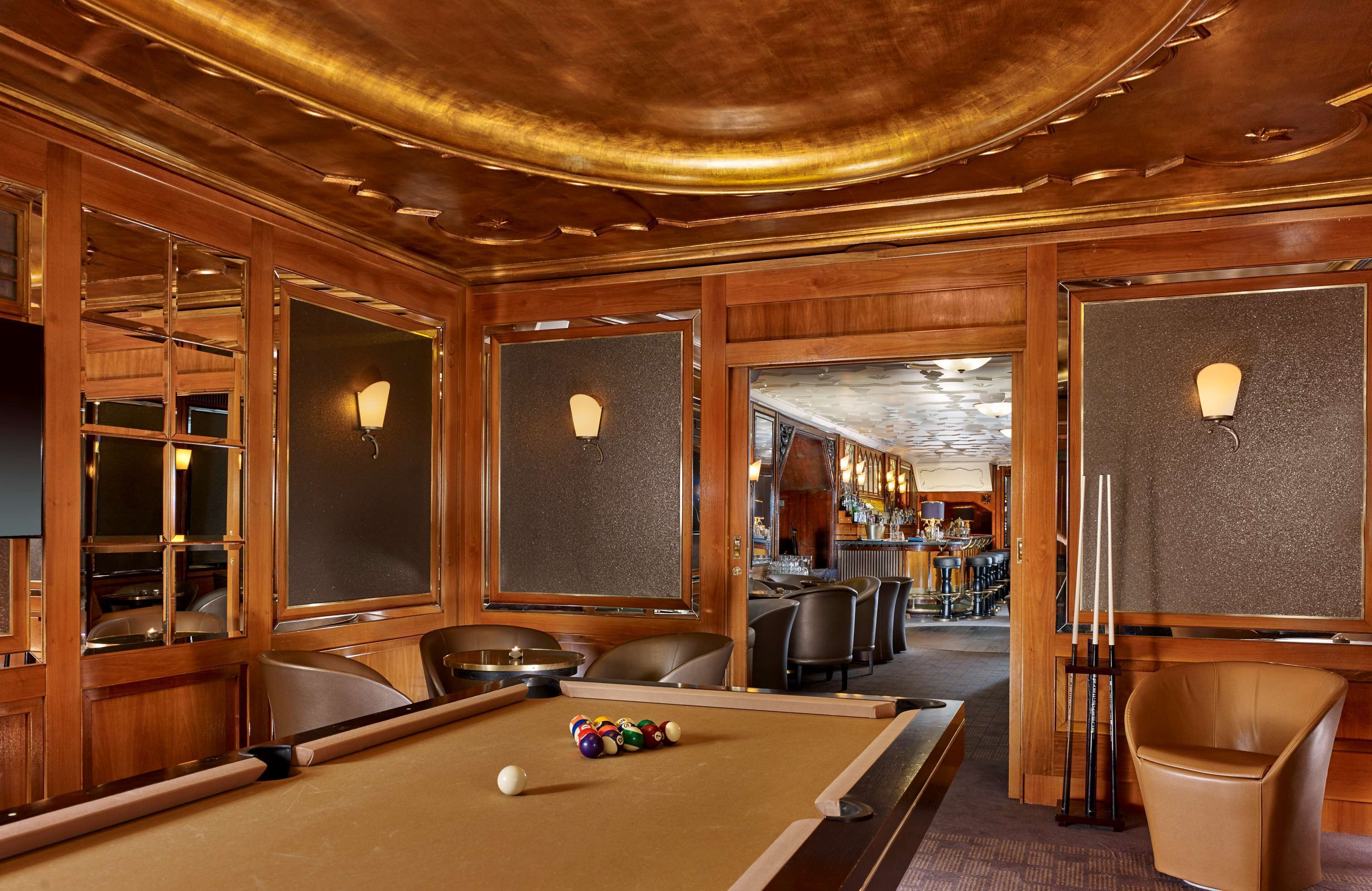 A pool table with balls, a bar area with stools, and a seating area with chairs.
