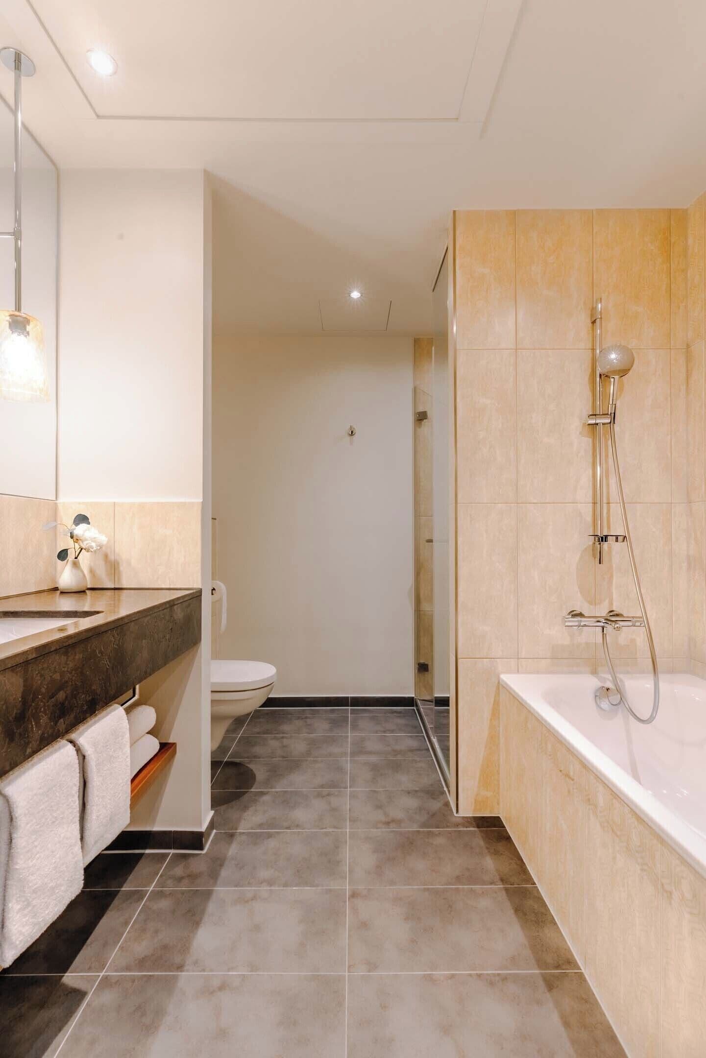 Ein modernes Badezimmer mit Badewanne, Dusche und Toilette.