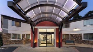 L’entrée d’un hôtel avec une porte en verre, une façade en pierre et une allée couverte.
