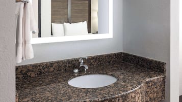 A bathroom with a granite countertop sink, a mirror, and a towel rack.