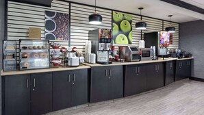 Un coin café équipé d’une machine à café, de tasses et d’un présentoir de viennoiseries.