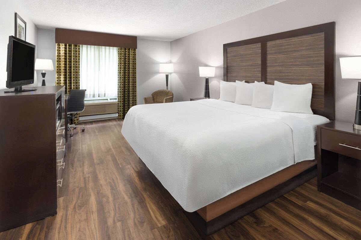 Une chambre d’hôtel avec un grand lit, un bureau équipé d’un ordinateur, une chaise et un téléviseur.
