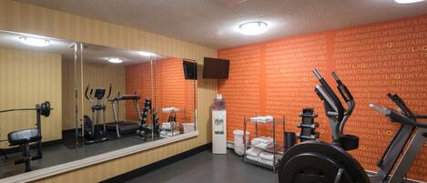 A gym with exercise equipment, a water dispenser, and a mirror.