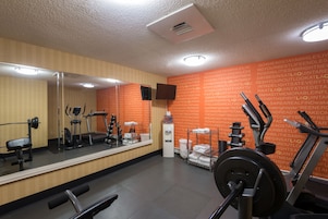 Un gimnasio con equipo de ejercicio, un dispensador de agua y un espejo.