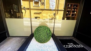 L’entrée d’un hôtel, avec une porte en verre, une sphère décorative verte et une enseigne indiquant « The Cortez ».