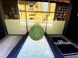 A hotel entrance with a glass door, a green spherical decoration, and a sign reading "The Cortez".