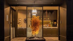 Un espace d’accueil doté d’une cloison en verre, d’un comptoir de réception, d’une horloge et d’une plante décorative.