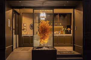 A reception area with a glass partition, a reception desk, a clock, and a decorative plant.
