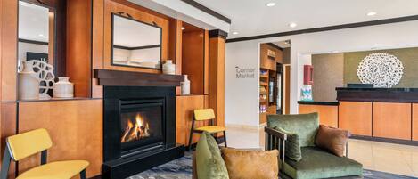 A hotel lobby with a fireplace, seating area, and a reception desk.