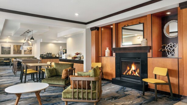 Eine Hotelhalle mit Kamin, Sitzgruppe und Essbereich.