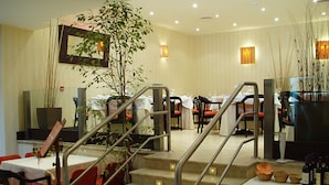 Un restaurante con una escalera que lleva a un comedor, mesas con manteles blancos y sillas.