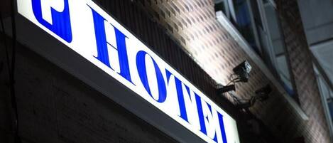 A hotel sign with the word "HOTEL" in large blue letters on a white background.