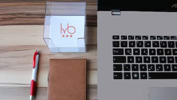 A laptop, a red and white pen, and a brown notebook on a wooden surface.