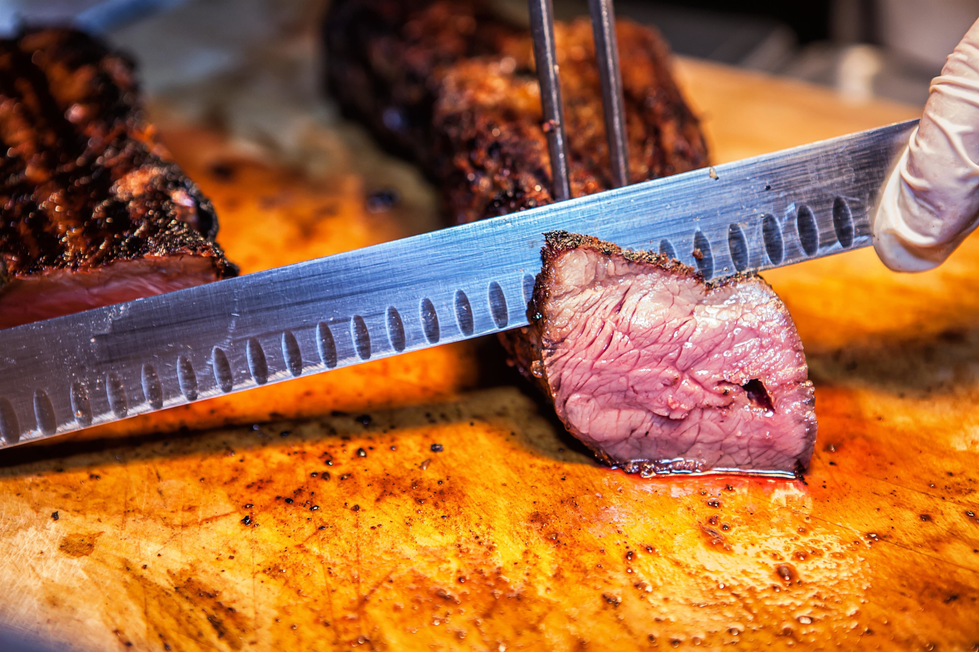 Ein Nahblick auf ein Steak, das mit einem Messer geschnitten wird.