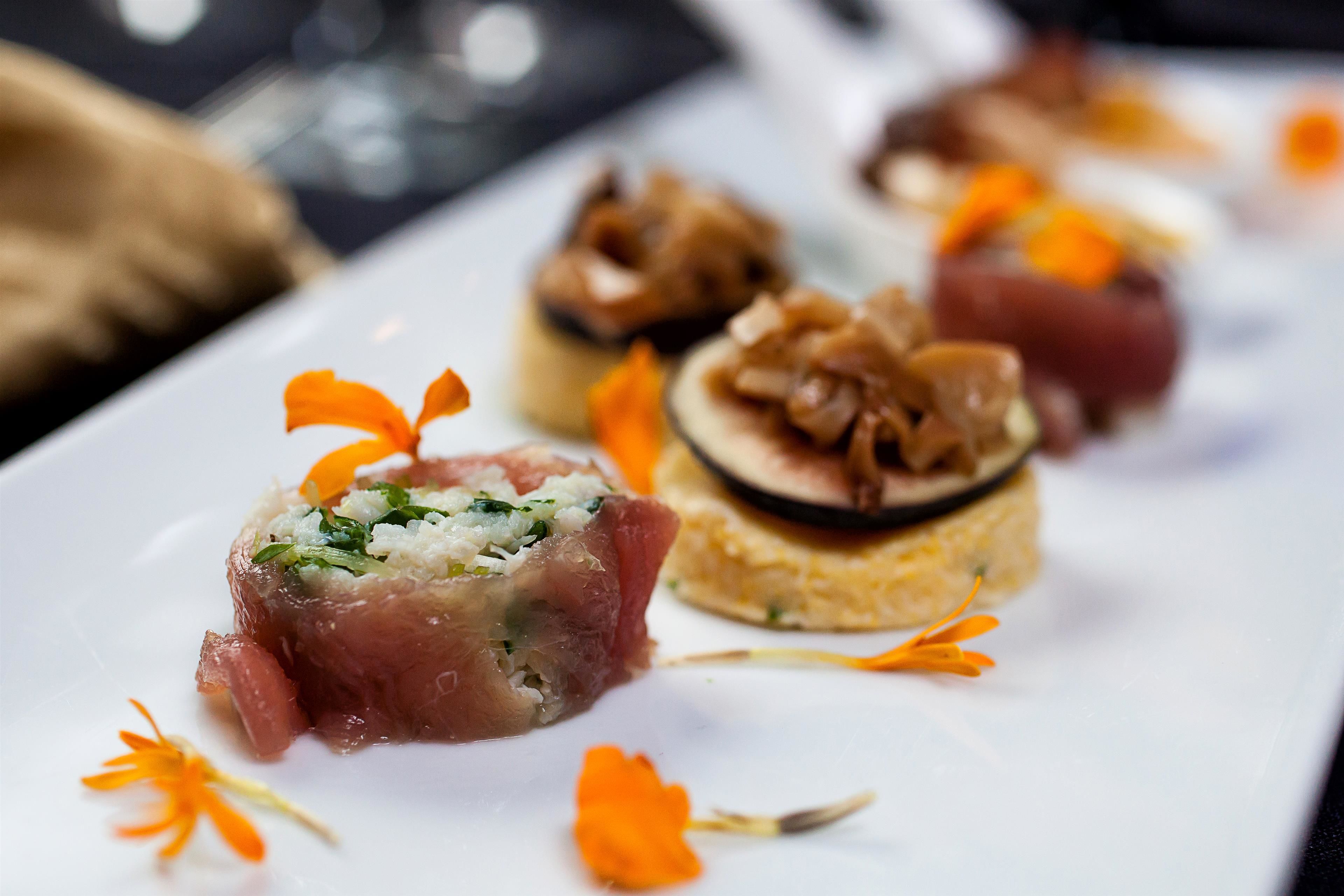 Un plato blanco con diferentes alimentos, entre ellos un trozo de carne y un plato redondo en capas.