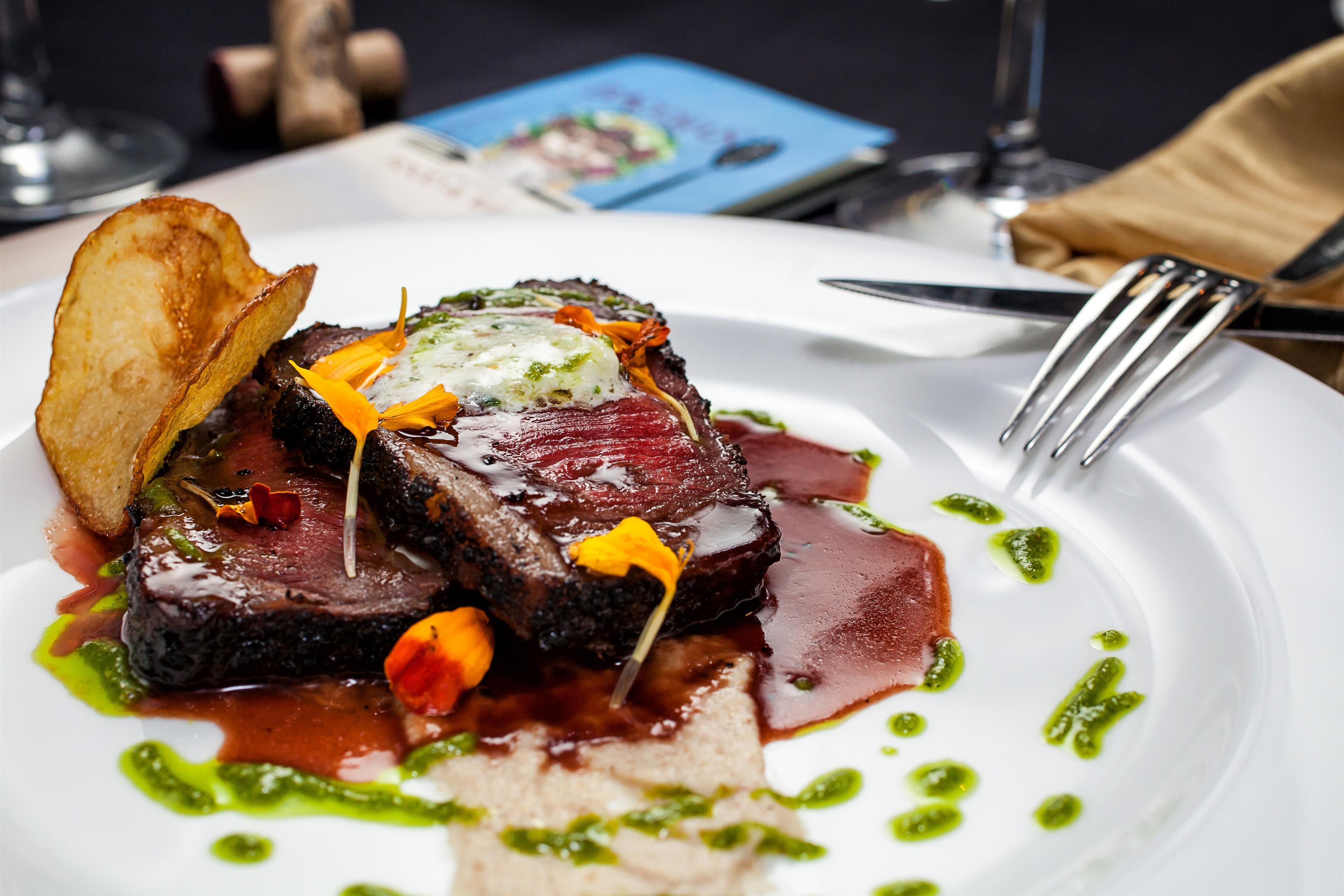 Une assiette de nourriture comprenant un steak, des légumes et une sauce.