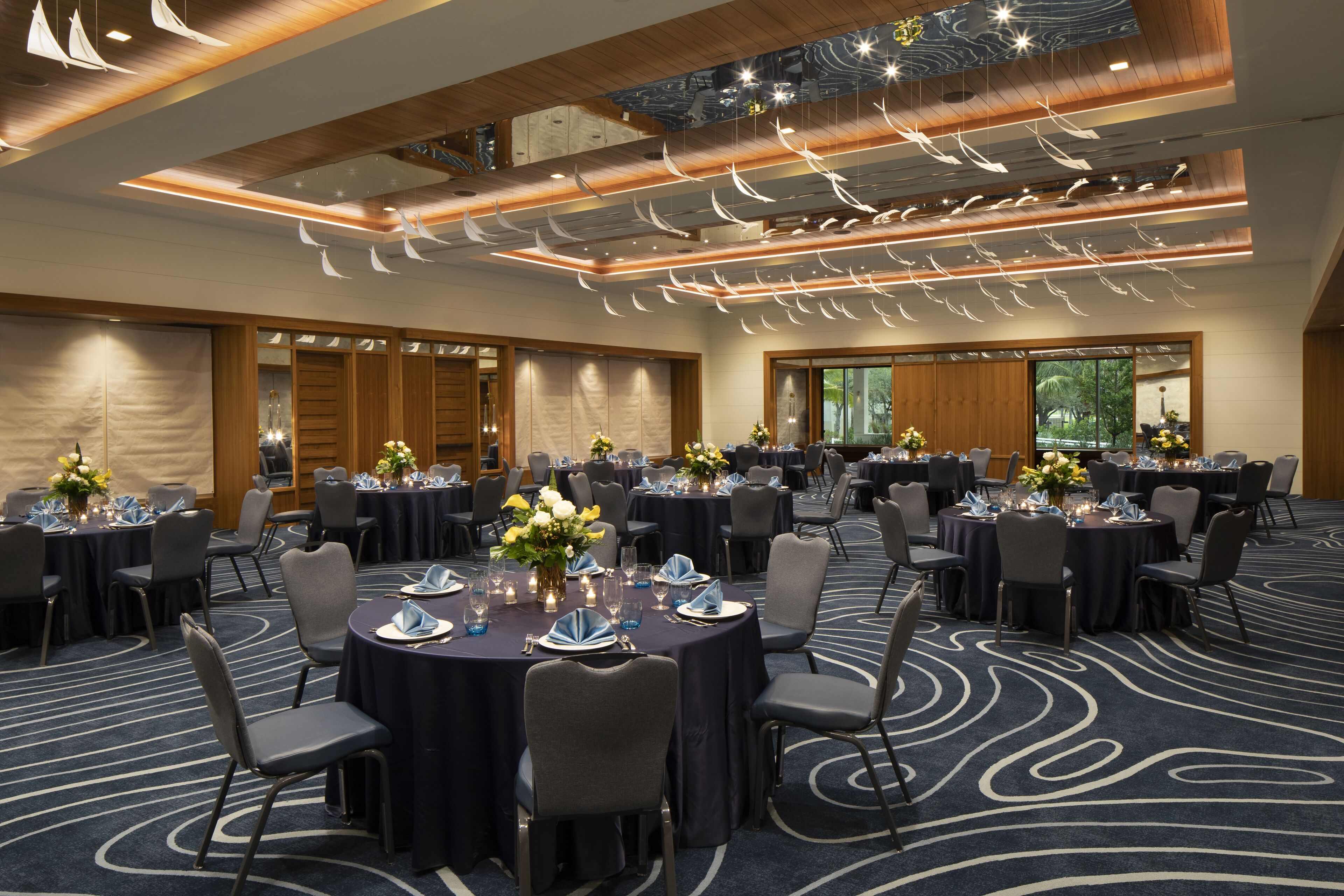 A conference room with round tables, chairs, and floral centerpieces.