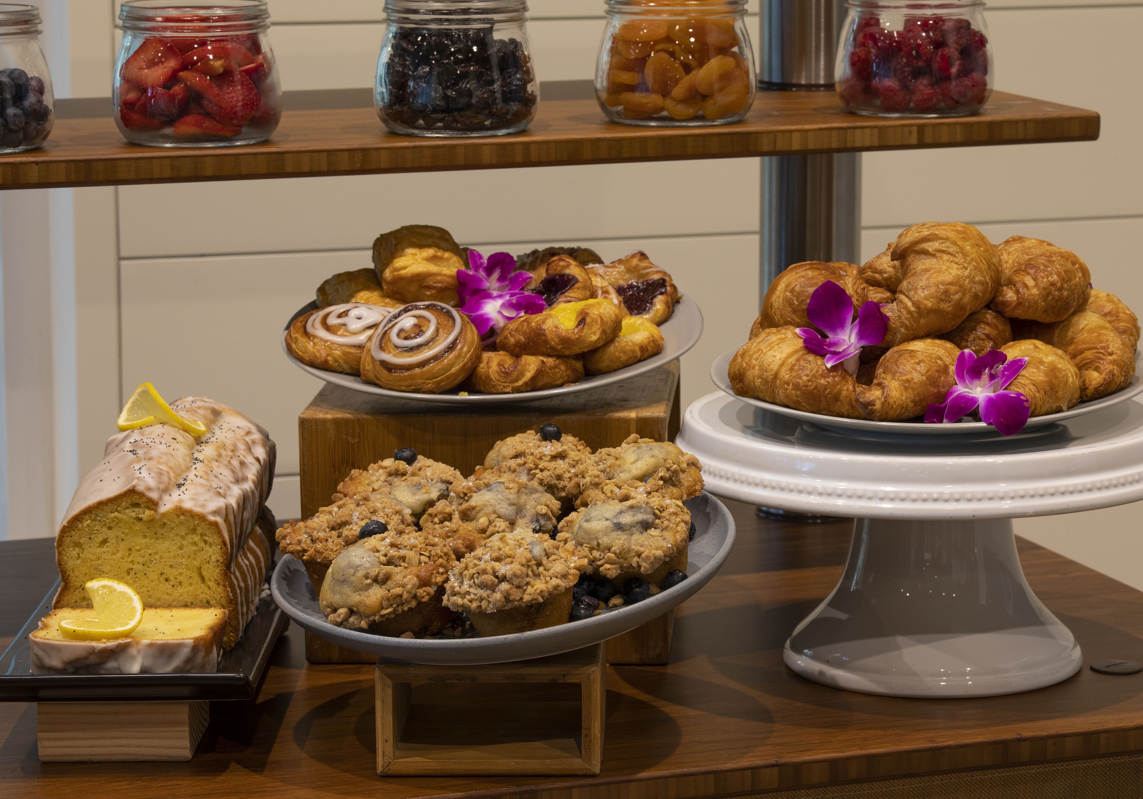 Una presentación de pasteles y mermeladas sobre una mesa de madera.