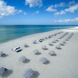 Relax on the pristine beach with rows of shaded lounge chairs and umbrellas.