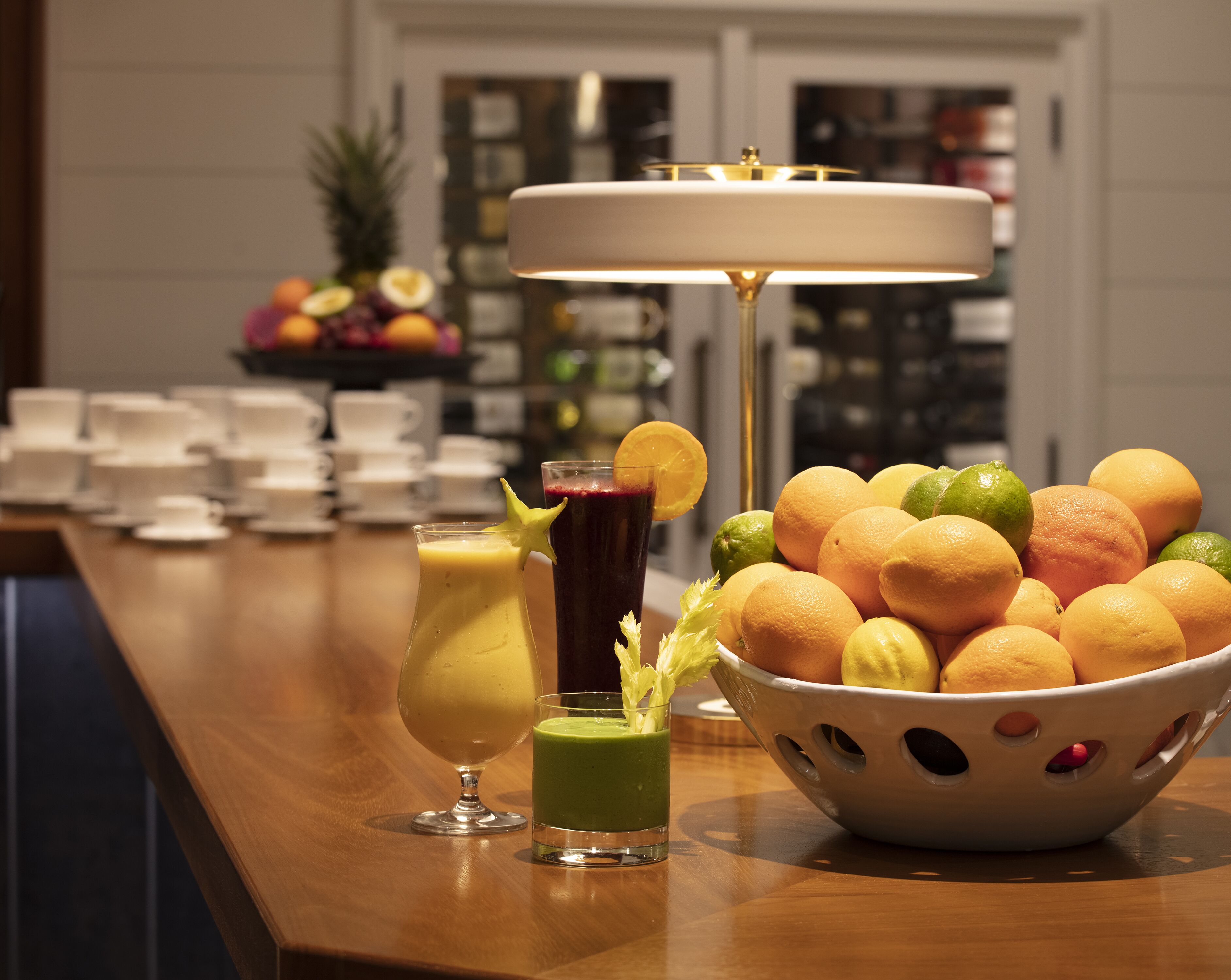 A bar area with a fruit bowl, two drinks, and a lamp.