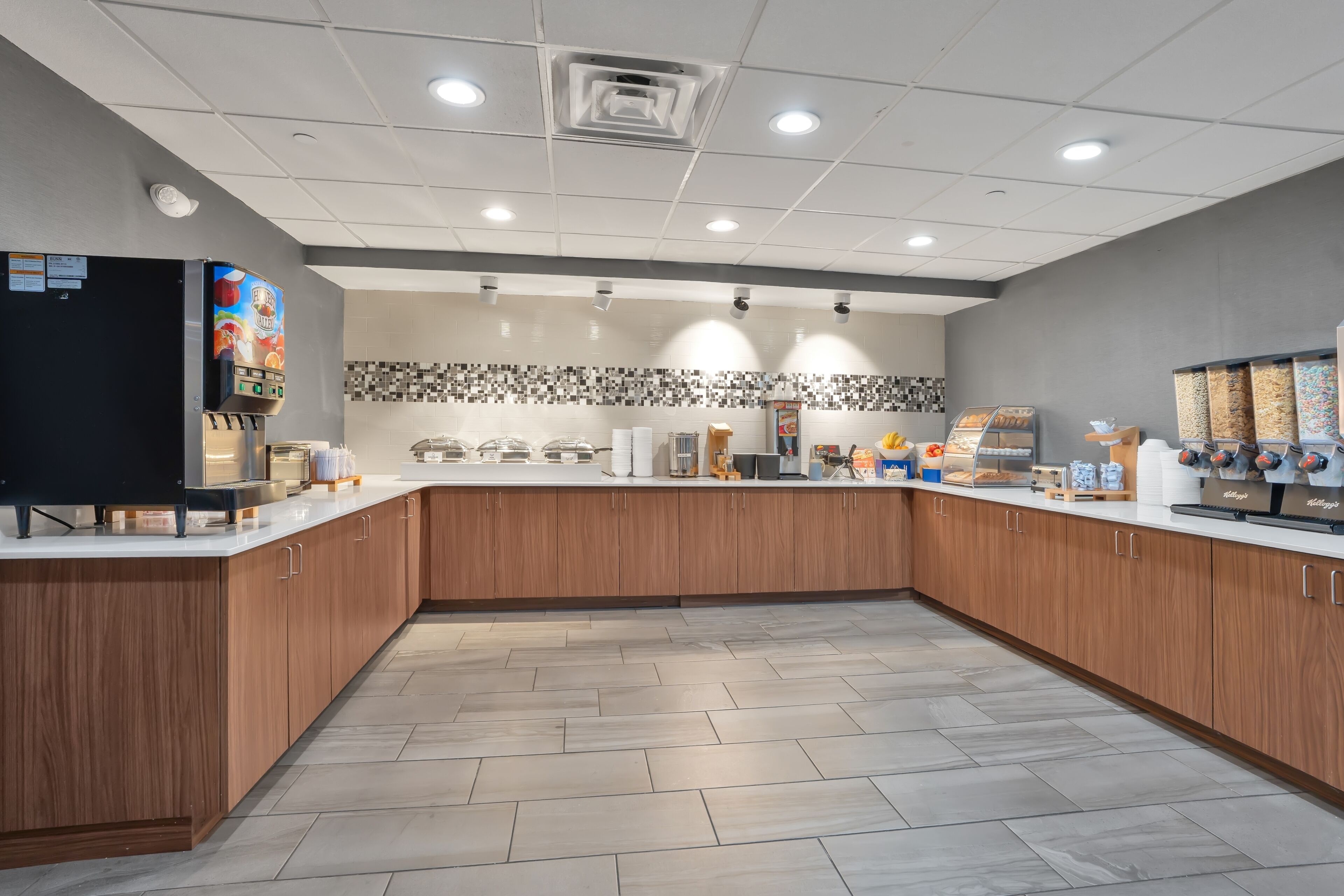 A modern kitchen with wooden cabinets, a coffee machine, and a tiled backsplash.