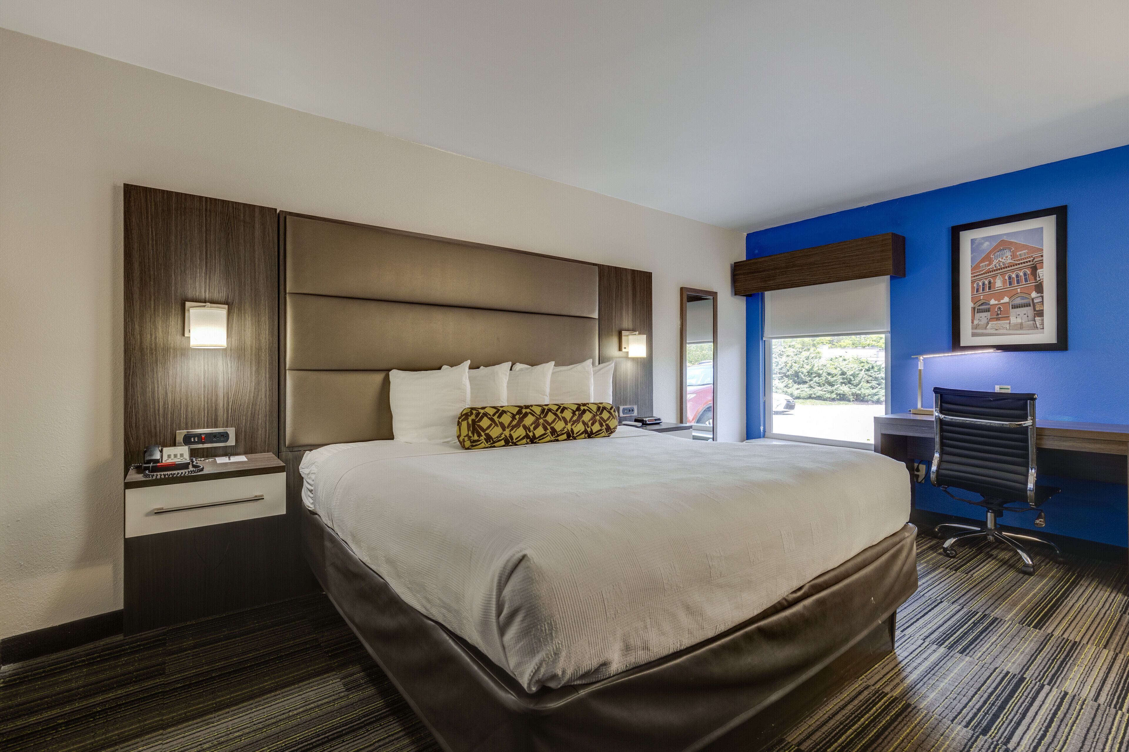 Een hotelkamer met een groot bed, een bureau, een stoel en een raam met uitzicht.
