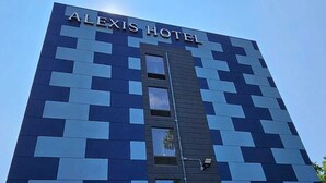 Un edificio alto con fachada a cuadros y el nombre "ALEXIS HOTEL" en la parte superior.