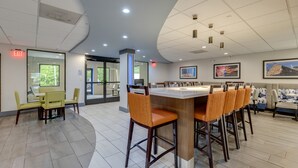 Un restaurante moderno con una zona de bar curva, techos altos y ventanas amplias.
