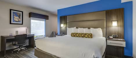 Habitación de hotel con una cama grande, un escritorio, una silla y una ventana con vistas.
